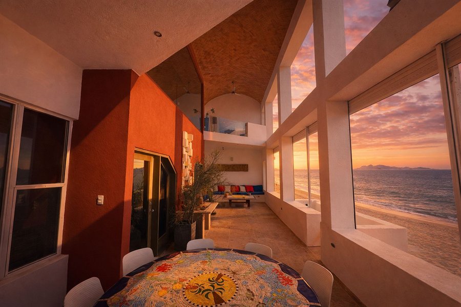 Interior de casa frente a la playa con comedor y ventanales al mar de Cortés al atardecer